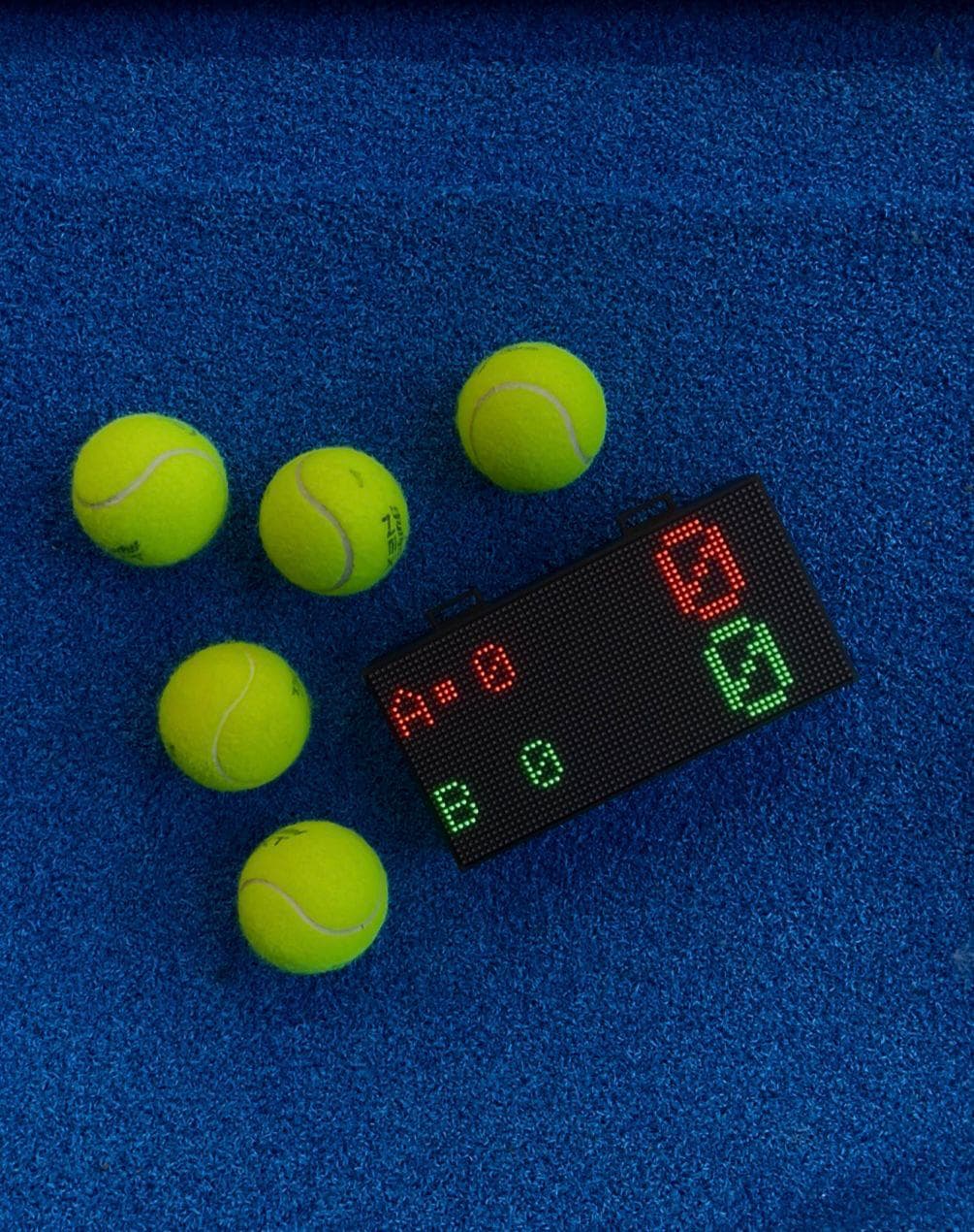 Le boîtier et cinq balles de padel sur le gazon bleu